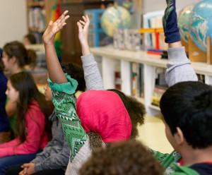 Students raising hands in a classroom